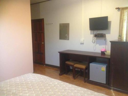 a bedroom with a desk with a television and a bed at สวนไผ่รีสอร์ท in Ban Na