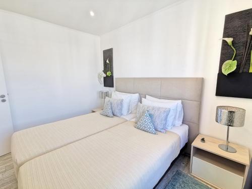 Duas camas num pequeno quarto com um candeeiro sobre uma mesa em Apartment Praia Rocha Waterside Blue em Portimão