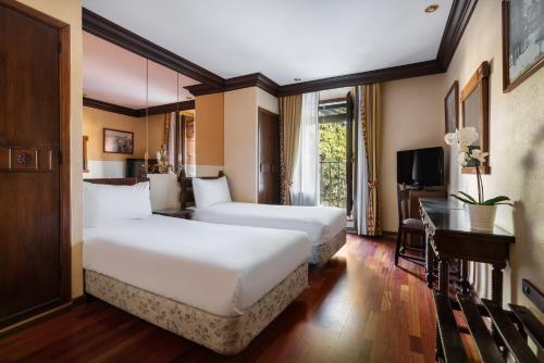 a hotel room with two beds and a television at Crisol Conde Rodrigo in Ciudad-Rodrigo