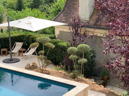- une piscine avec un parasol et une chaise dans l'établissement La Maison Carrée - Villa de charme - Clim & Piscine chauffée, à Les Eyzies-de-Tayac