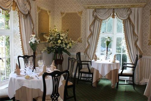 uma sala de jantar com duas mesas e cadeiras com flores em Maenan Abbey Hotel em Llanrwst