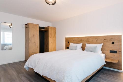 a bedroom with a large white bed with a wooden headboard at Moderne 2 Zi.-FeWo BlackForest Art Barrierefrei Nähe Freiburg in Simonswald
