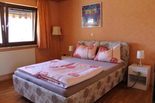 um quarto com uma cama com cobertores e almofadas cor-de-rosa em urgemütliche Ferienwohnung im Kraichgauer Hügelland em Eppingen