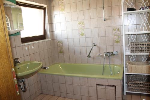 uma casa de banho com uma banheira verde e um lavatório em urgemütliche Ferienwohnung im Kraichgauer Hügelland em Eppingen