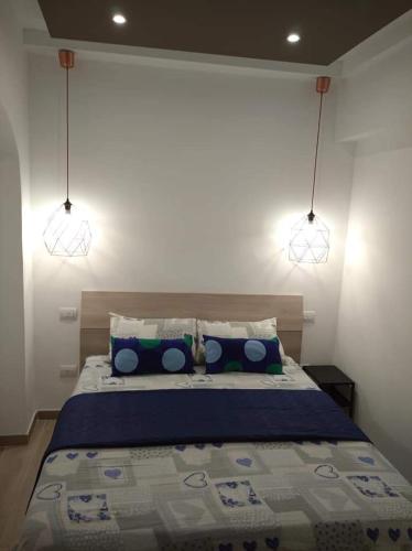 a bedroom with a bed with blue pillows and two lights at Mattia's house 2 in Bari
