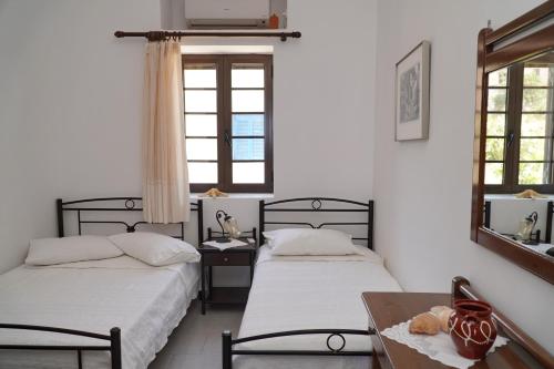 two beds in a room with a table and two windows at Moutsouna Beach in Moutsouna Naxos
