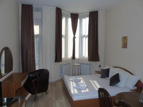 a living room with a white bed and a desk at Хотел Флора private studio All seasons in Borovets