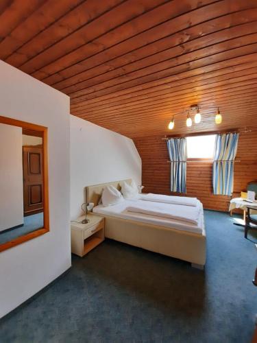 a bedroom with a large bed with a wooden ceiling at Pension Kreuzinger, 5310 Tiefgraben in Mondsee