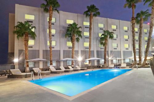 une piscine avec des palmiers en face d'un hôtel dans l'établissement Holiday Inn - Ciudad Juarez, an IHG Hotel, à Ciudad Juárez