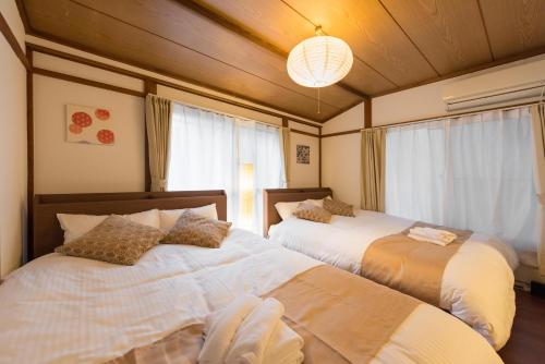 東京にあるYoshinaga heightsのベッド2台とシャンデリアのある寝室