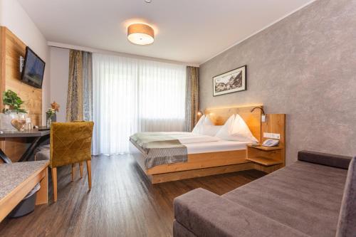 ein Hotelzimmer mit einem Bett und einem Schreibtisch in der Unterkunft Hotel Almrausch in Saalbach-Hinterglemm