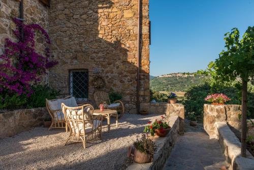 a patio with chairs and a table and flowers at Agriturismo Schiaccia Ghiande in Massa Marittima