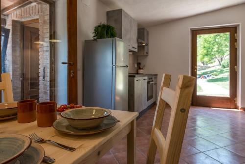 a kitchen with a table with a stainless steel refrigerator at Agriturismo Schiaccia Ghiande in Massa Marittima