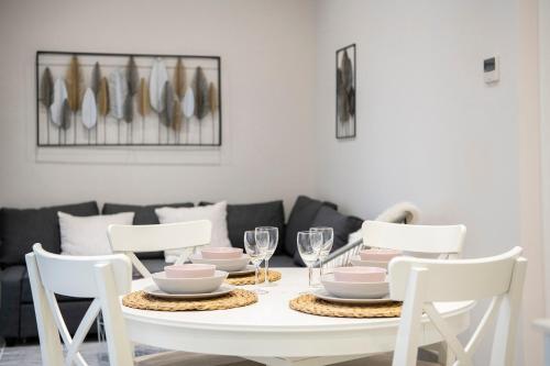 a white dining room table with white chairs and plates and glasses at Lovely & Cozy apartment in the heart of Banyoles in Banyoles
