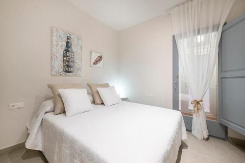 a white bedroom with a white bed and a window at Lovely & Cozy apartment in the heart of Banyoles in Banyoles