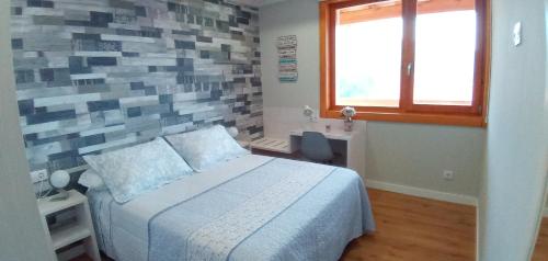 ein Schlafzimmer mit einem Bett und einer Ziegelwand in der Unterkunft El Mirador de Bodes in Bodes