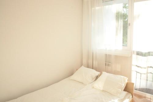 Una cama blanca en una habitación con ventana. en Apartament Sen, en Łódź