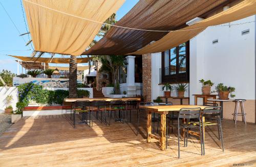 a patio with wooden tables and chairs under a canopy at Hostal Illes Pitiüses in Sant Ferran de Ses Roques