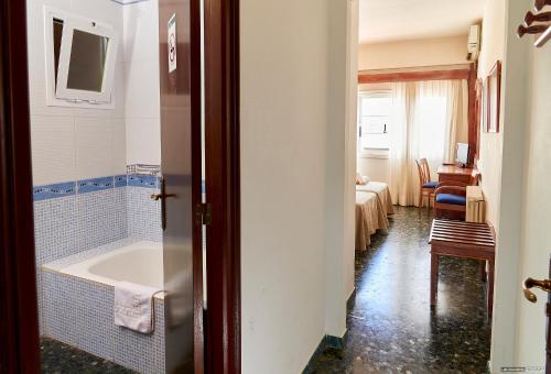 a bathroom with a bath tub and a bedroom at Hostal Illes Pitiüses in Sant Ferran de Ses Roques