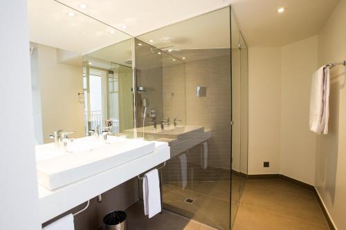 a bathroom with two sinks and a glass shower at Hôtel des Voyageurs Boutique in Lausanne