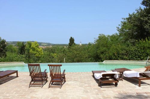 a swimming pool with chairs and a table and a swimming pool at Castello Montegiove in Fano