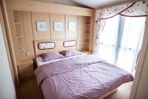 Un dormitorio con una cama con sábanas moradas y una ventana en Domeček pod Ralskem, en Pertoltice pod Ralskem