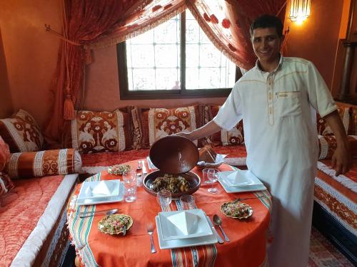 a man standing in front of a table with food at Dar Assarou - Toubkal National Park Lodge in Imlil