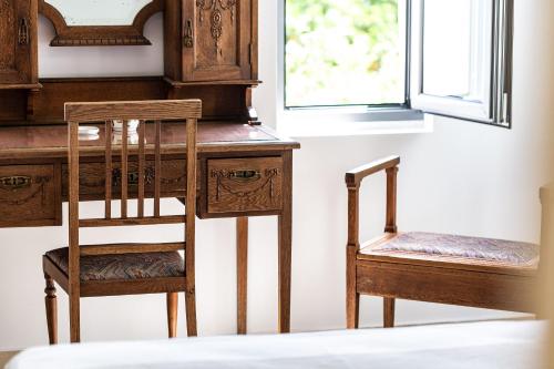 two wooden chairs sitting next to a desk and a window at Muazzo Historic Residence, in the Village Core, By ThinkVilla in Pigi