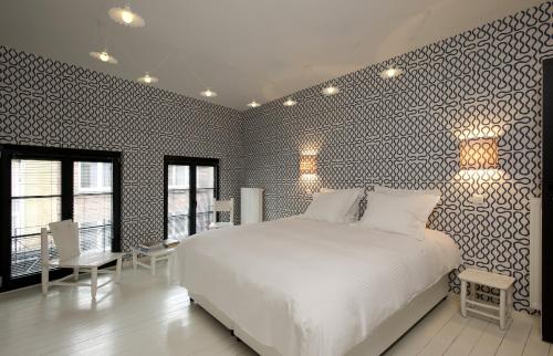- une chambre avec un lit blanc et un mur noir et blanc dans l'établissement La Maison Haute guesthouse, à Bruxelles