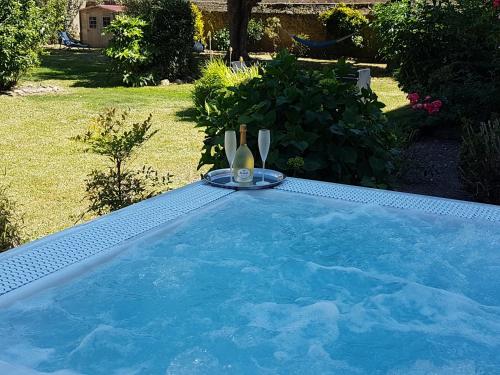 a swimming pool with a table and a bottle of wine at Hôtel Spa De La Citadelle Lorient in Port-Louis