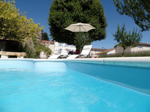 - une piscine bleue avec un parasol et des chaises dans l'établissement Le Four à Pain, à Saint-Jean-dʼAngély