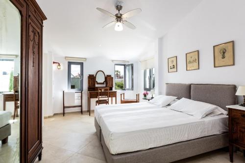 a white bedroom with a bed and a dining room at Muazzo Historic Residence, in the Village Core, By ThinkVilla in Pigi
