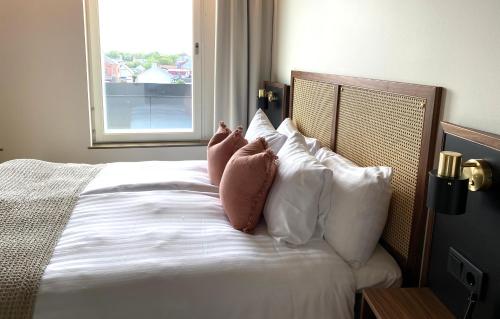 two people laying on top of a bed with pillows at Fritiden Hotell & Kongress in Ystad