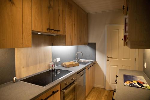 a kitchen with wooden cabinets and a sink and a counter at Chalet à l'aise met Wellness, Durbuy in Durbuy