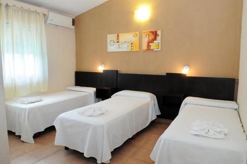 3 Betten in einem Hotelzimmer mit weißer Bettwäsche in der Unterkunft Hotel El Faro in Villa Carlos Paz