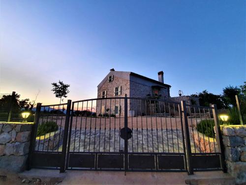 ein altes Haus hinter einem Tor in der Nacht in der Unterkunft Stone House Rosuja in Ivanje