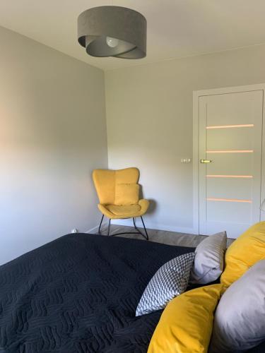 um quarto com uma cama e uma cadeira amarela em Centropolis 41 em Toruń