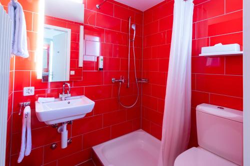 a red bathroom with a sink and a toilet at Hotel Bauernhof - Self Check-In Hotel in Rotkreuz