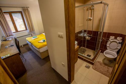 een badkamer met een douche, een toilet en een bed bij Apartments Tango in Kolašin