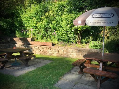 zwei Picknicktische und ein Regenschirm im Gras in der Unterkunft The White Horse Inn, Clun in Clun