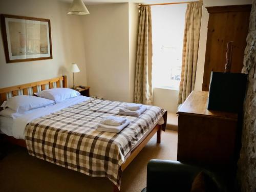 a bedroom with a bed with a checkered blanket at The White Horse Inn, Clun in Clun