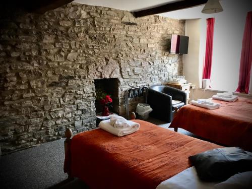 a room with two beds and a stone wall at The White Horse Inn, Clun in Clun