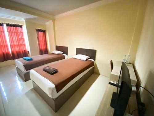 Hotel Grand Citra Prabumulih في Perabumulih: غرفة نوم بسريرين وتلفزيون فيها