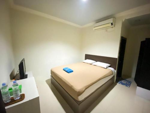 Hotel Grand Citra Prabumulih في Perabumulih: غرفة نوم صغيرة بها سرير وبعض زجاجات المياه