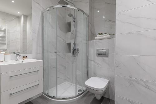 a bathroom with a shower and a toilet and a sink at Symphony Baltica Towers Apartamenty in Gdańsk