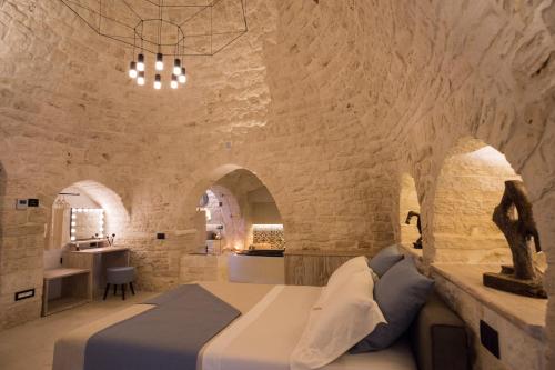 1 dormitorio con 1 cama en una pared de piedra en La Mandorla Luxury Trullo en Alberobello