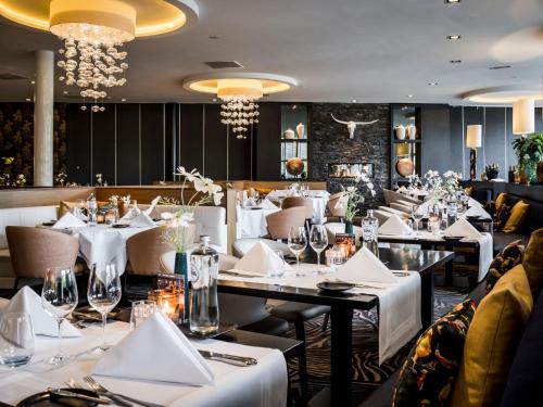 a restaurant with white tables and chairs and chandeliers at Hotel Van der Valk Maastricht in Maastricht