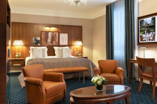 a hotel room with a bed and chairs and a table at Hôtel Barrière Le Westminster in Le Touquet-Paris-Plage