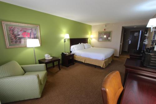 a hotel room with a bed and a couch and a chair at Baymont Inn & Suites by Wyndham Findlay in Findlay