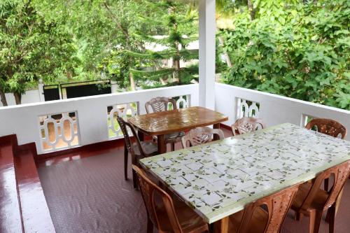 a porch with two tables and chairs and trees at Willwin Park in Anuradhapura